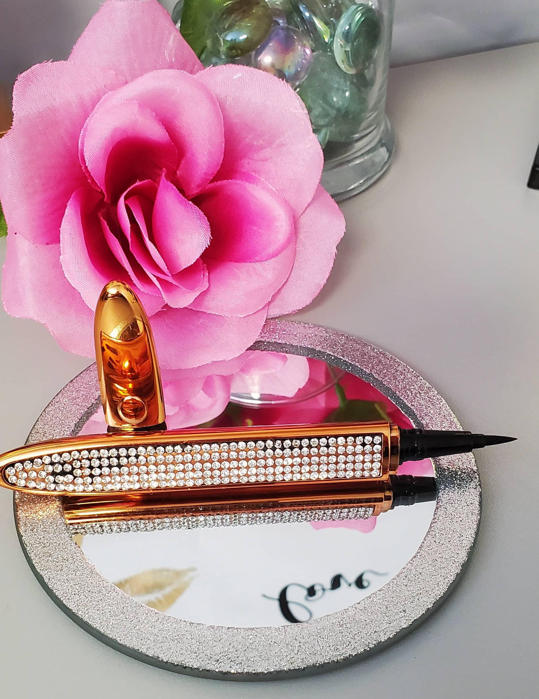 Black eyeliner adhesive pen in a gold diamond case.